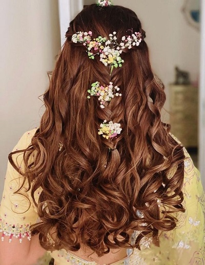 Half updo curly hairstyle with floral accent