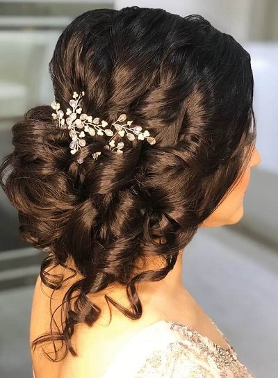 Low twisted French bun with loose curls